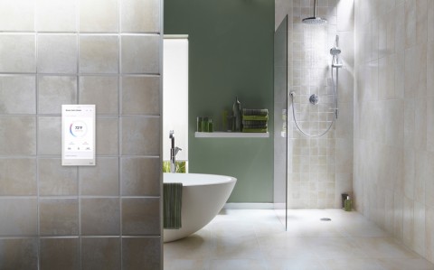 A bathroom with a Crestron smart control panel on the wall displaying the temperature. 