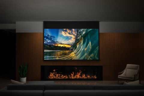 A media room with a projector screen hung above a modern fireplace.