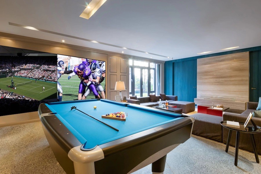 pool table in a game room featuring split-screen media coverage on a large display.