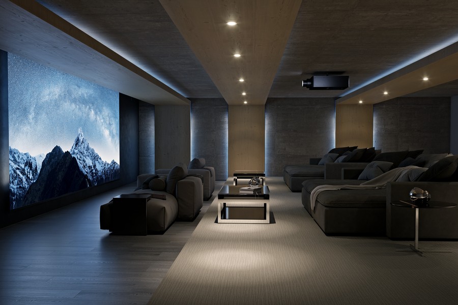 A home theater with chaise lounges, a large movie screen depicting snow-capped mountains, and a Sony projector.