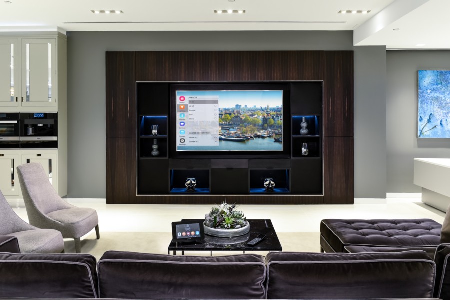 Living area with a flat-screen TV and touchscreen on the coffee table displaying the Crestron automation interface. 